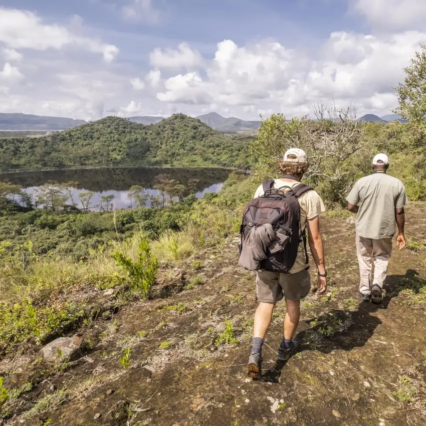 Hikers trekking through woodland with river valley landscape views, Rift Valley Lakes, Kenya