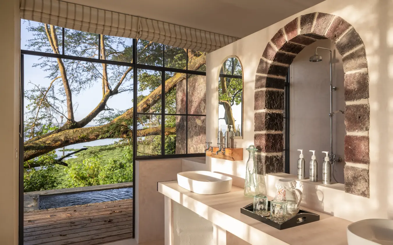 Luxury bathroom with arched brick shower overlooking treetops and water view, Loldia House, Rift Valley Lakes, Kenya