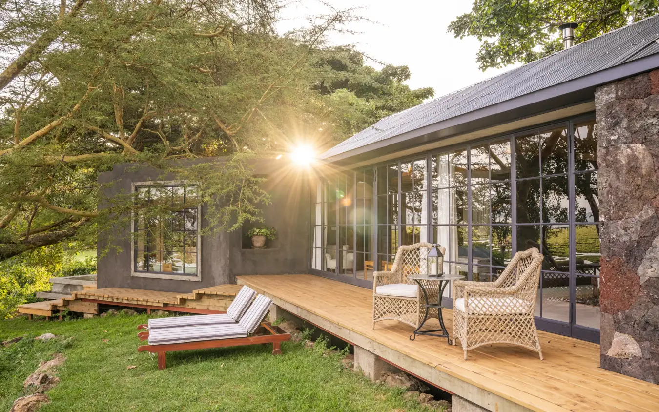 Modern glass pavilion with wooden deck overlooking manicured gardens at sunset, Loldia House, Rift Valley Lakes, Kenya