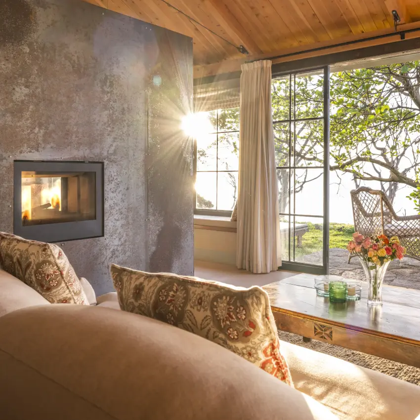 Modern living room with fireplace overlooking landscape through glass doors, Loldia House, Rift Valley Lakes, Kenya