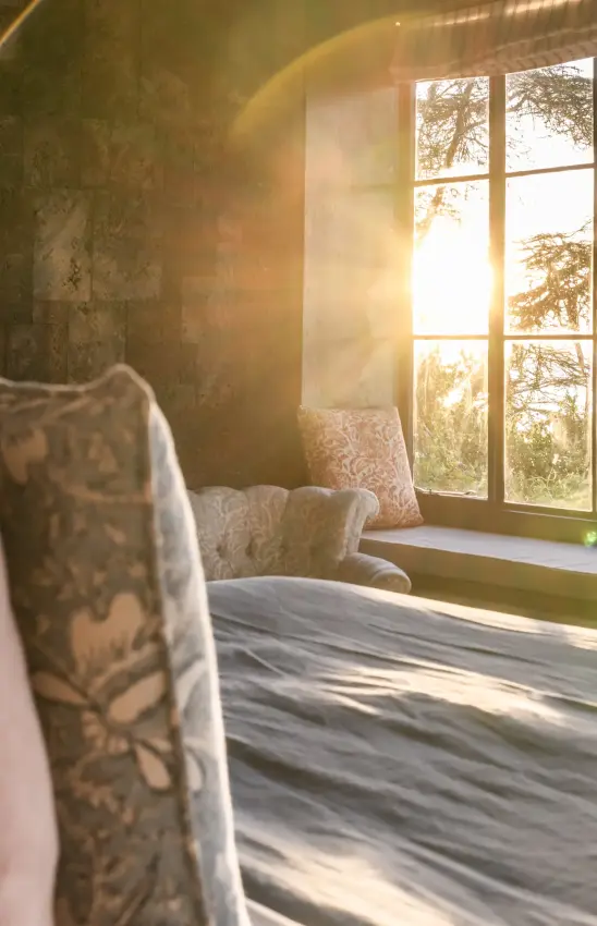 Bedroom with sunlit window overlooking autumn woodland landscape, Loldia House, Rift Valley Lakes, Kenya
