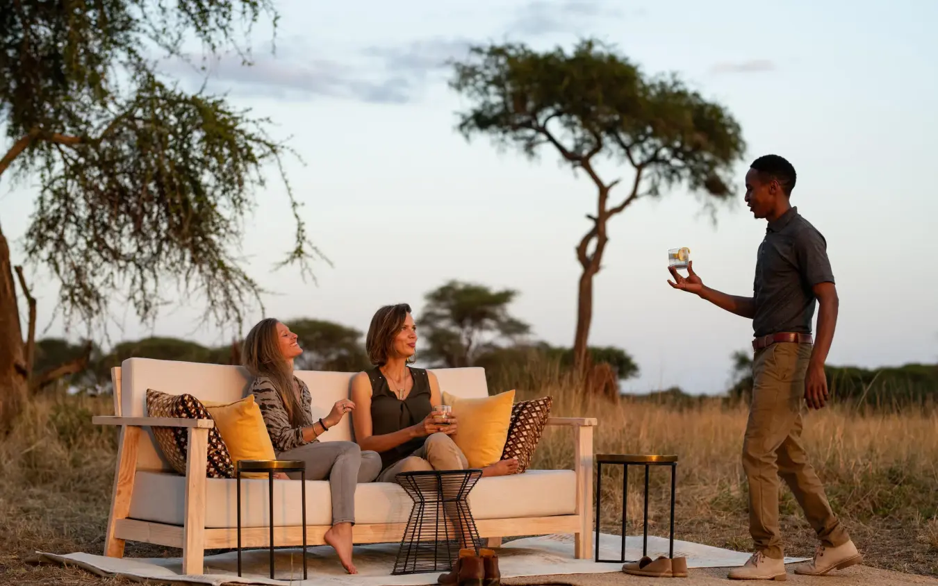 Guests relaxing on outdoor furniture in savanna setting, Lolkisale Camp, Tarangire National Park, Tanzania
