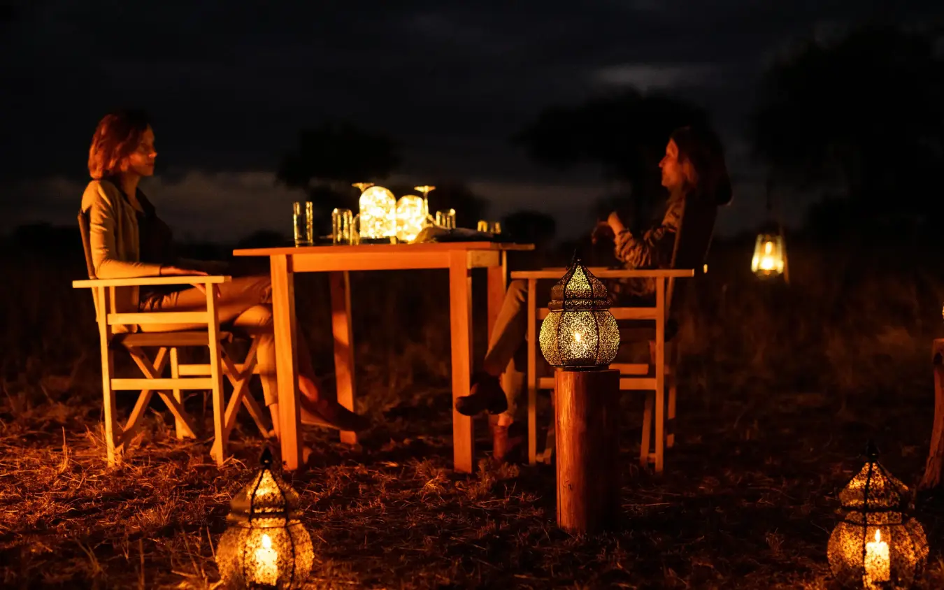 Two guests dining at candlelit table under night sky, Lolkisale Camp, Tarangire National Park, Tanzania