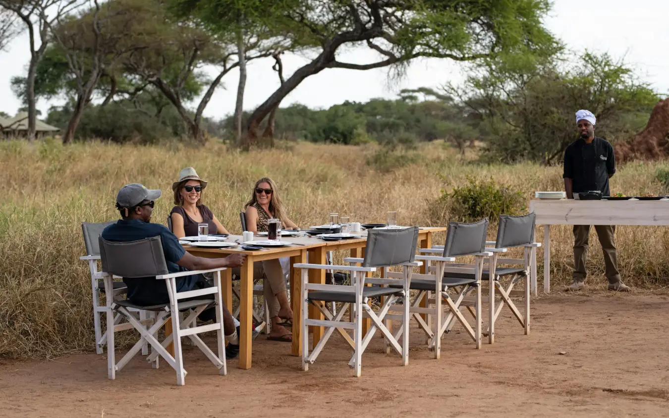 Outdoor dining setup in savanna landscape with acacia trees, Lolkisale Camp, Tarangire National Park, Tanzania
