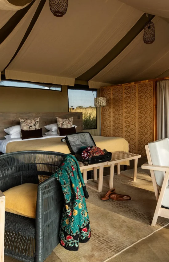 Glamping tent interior with bed and seating area, Lolkisale Camp, Tarangire National Park, Tanzania