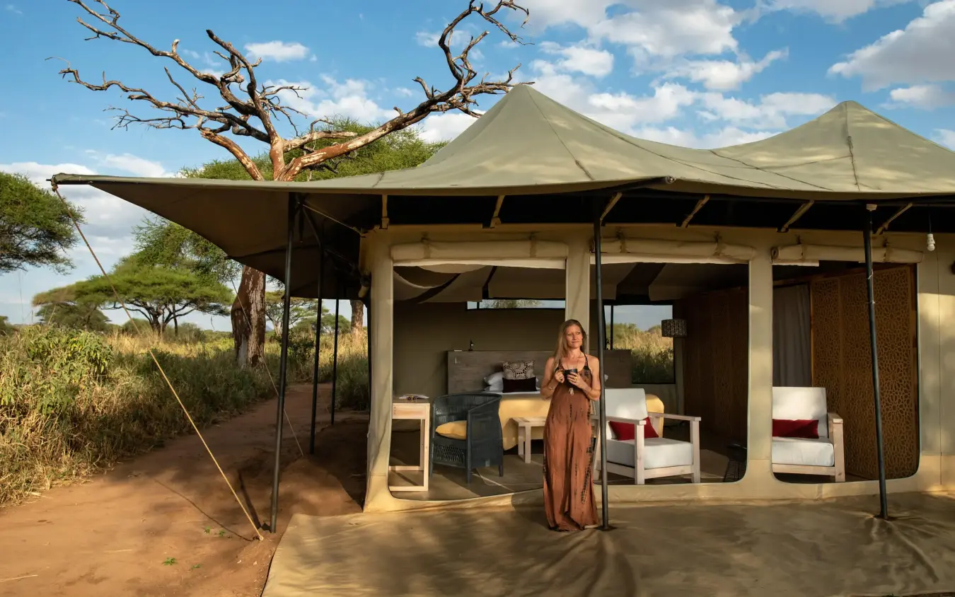 Canvas guest tent with woman standing on wooden deck, Lolkisale Camp, Tarangire National Park, Tanzania