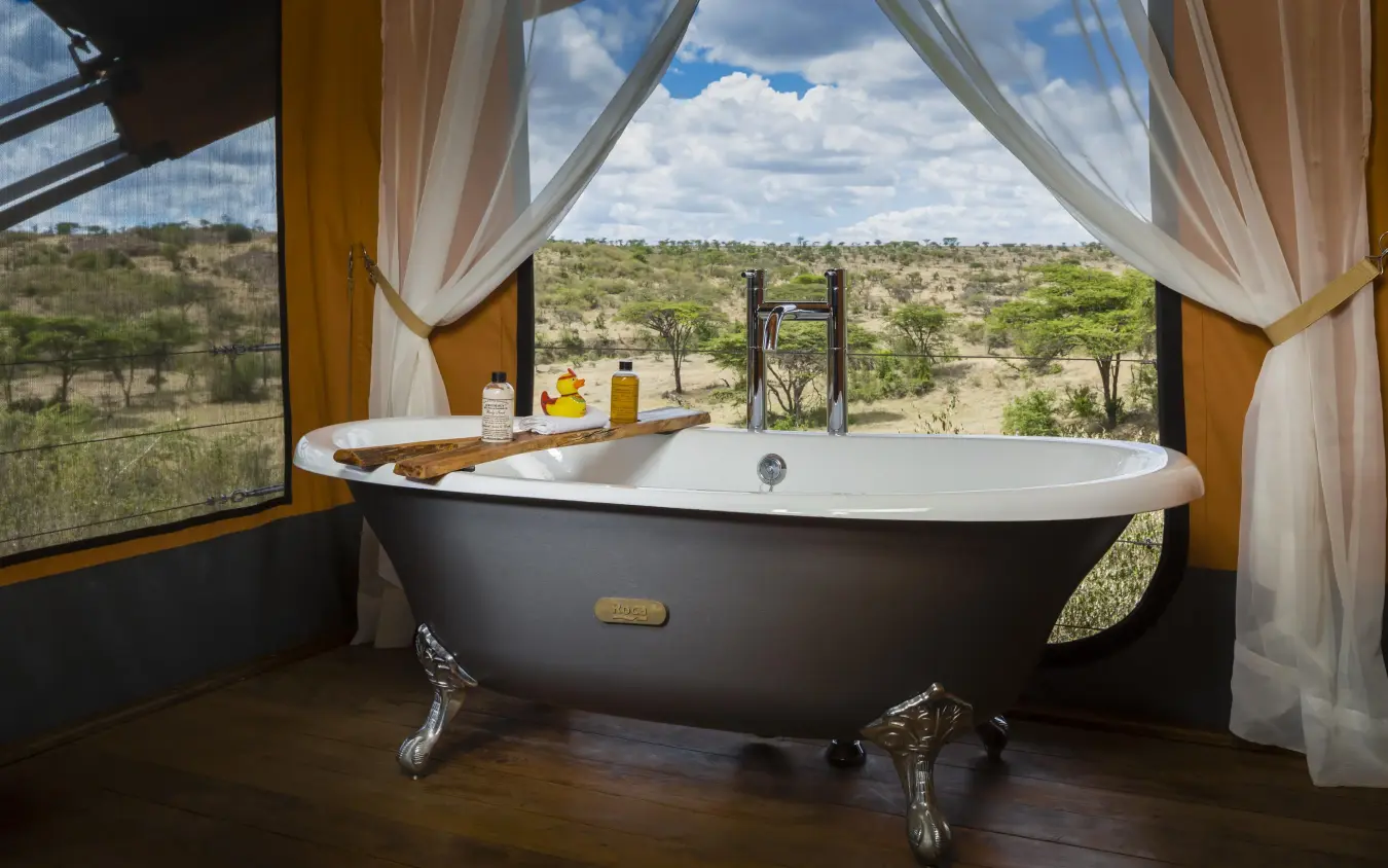 Freestanding bathtub with savanna landscape view through windows, Mahali Mzuri, Maasai Mara, Kenya