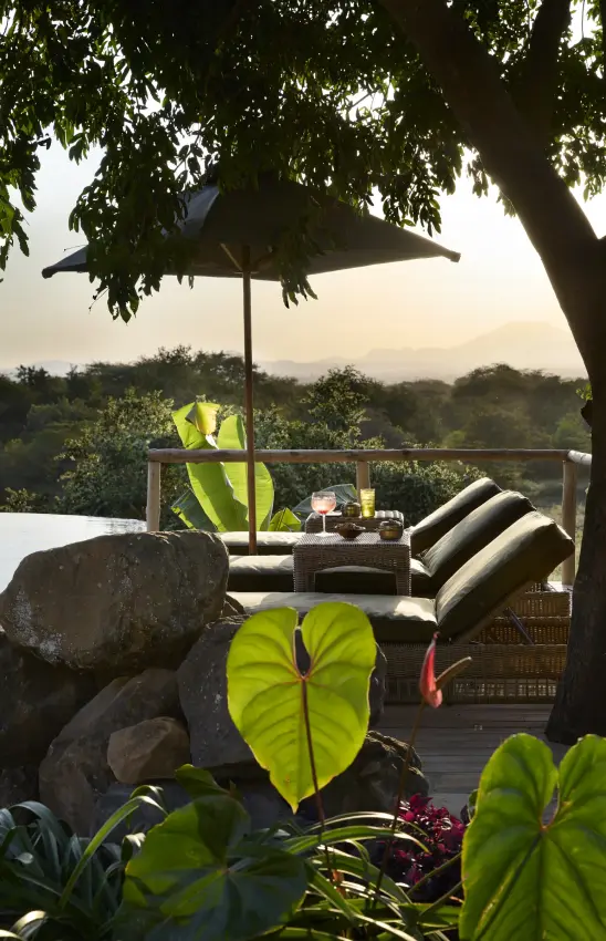 Luxury deck with umbrella and loungers overlooking forested valley at dusk, Mama Simba, Arusha, Tanzania