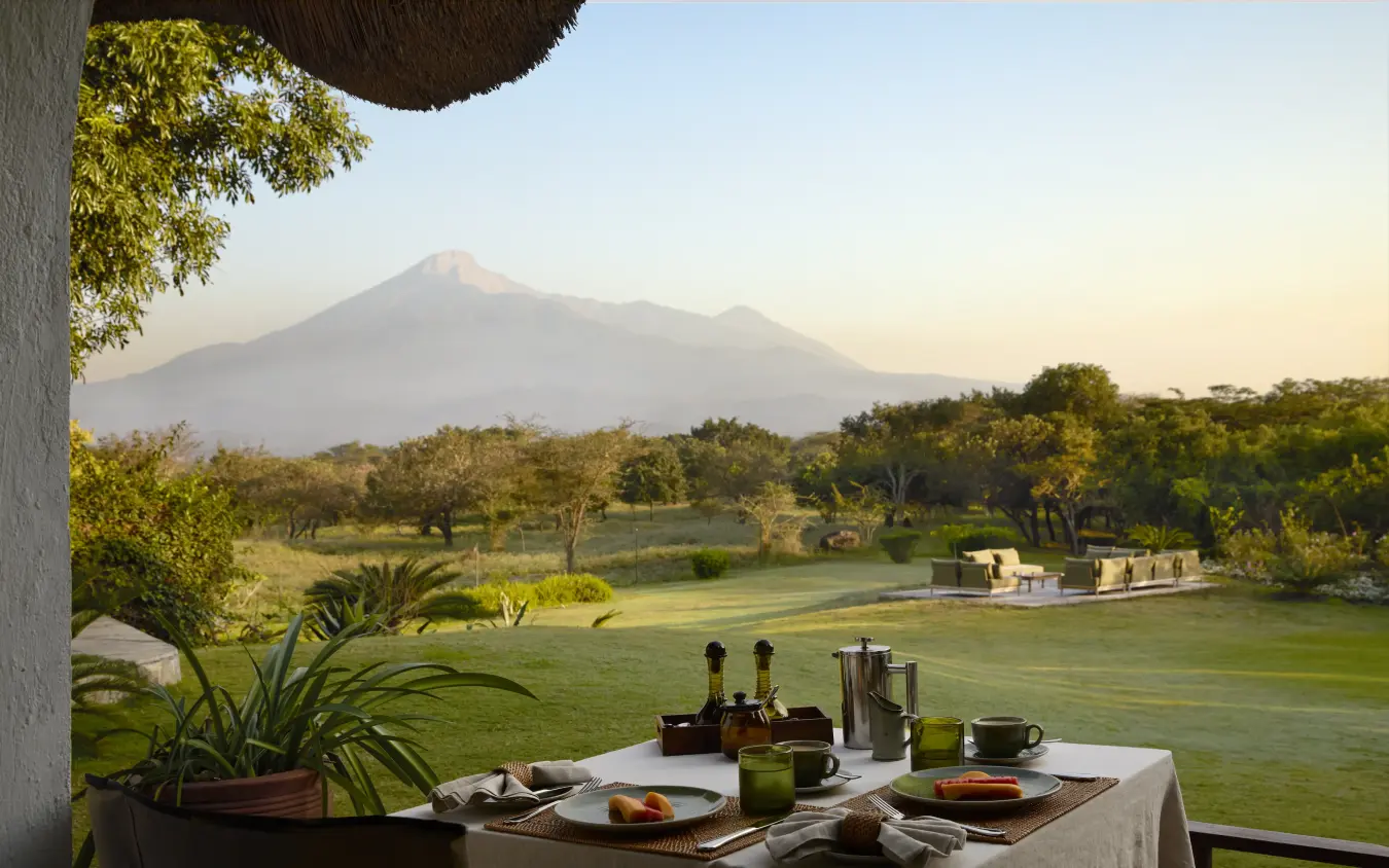 Dining table with mountain view across grassland and river, Mama Simba, Arusha, Tanzania