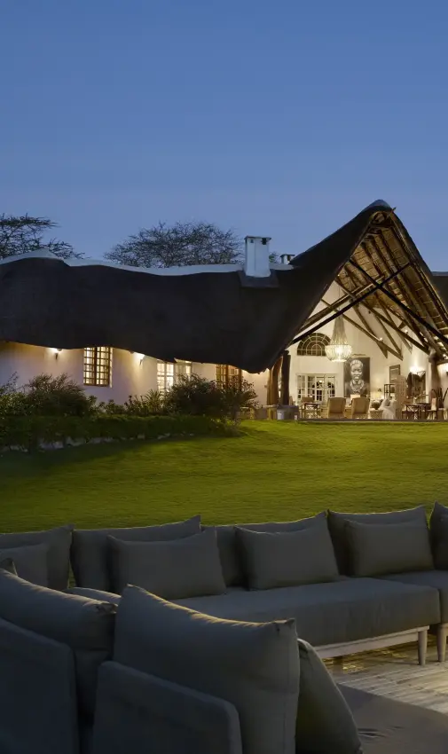 Luxury lodge with thatched roof and outdoor seating area at dusk, Mama Simba, Arusha, Tanzania