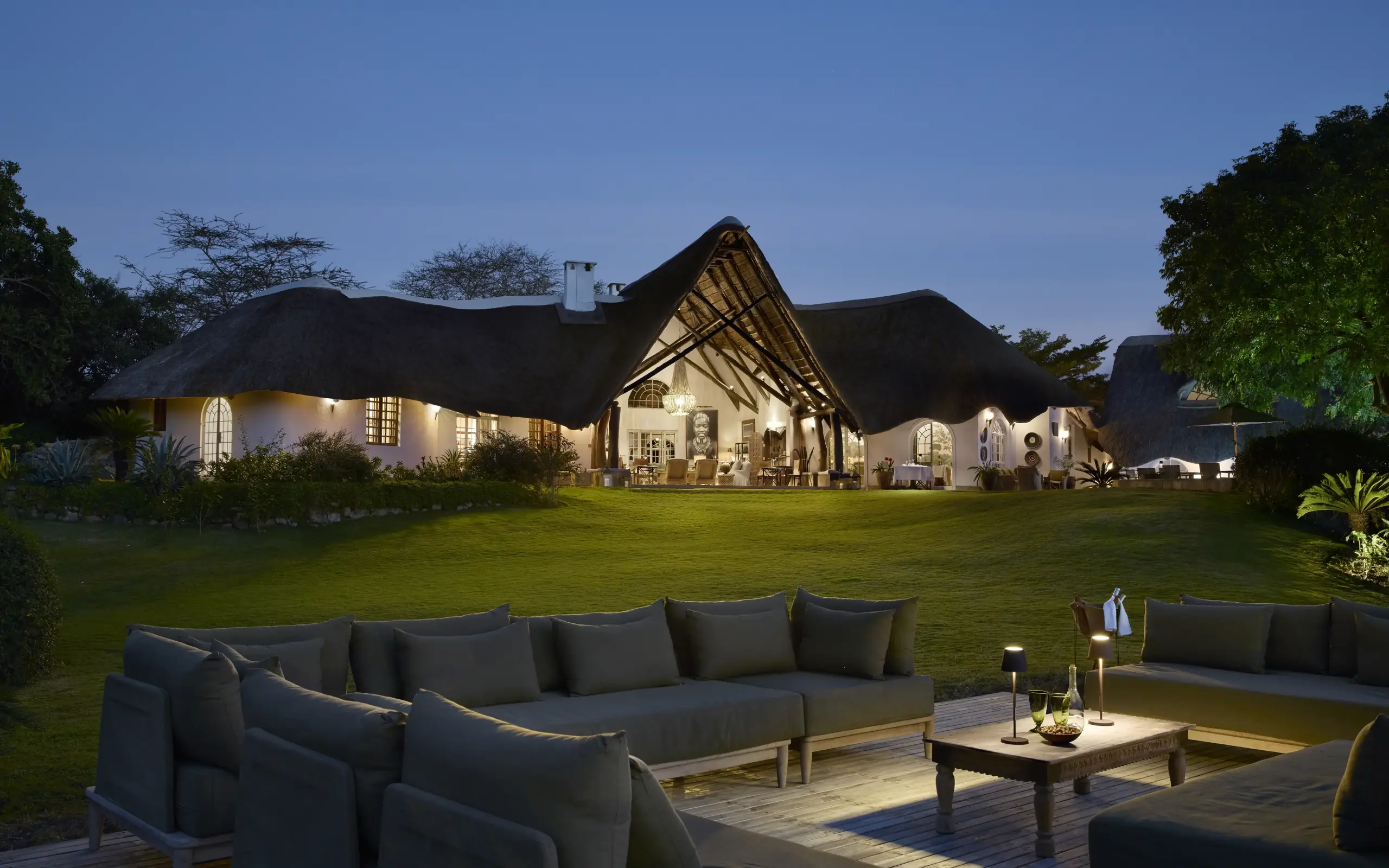 Luxury lodge with thatched roof and outdoor seating area at dusk, Mama Simba, Arusha, Tanzania