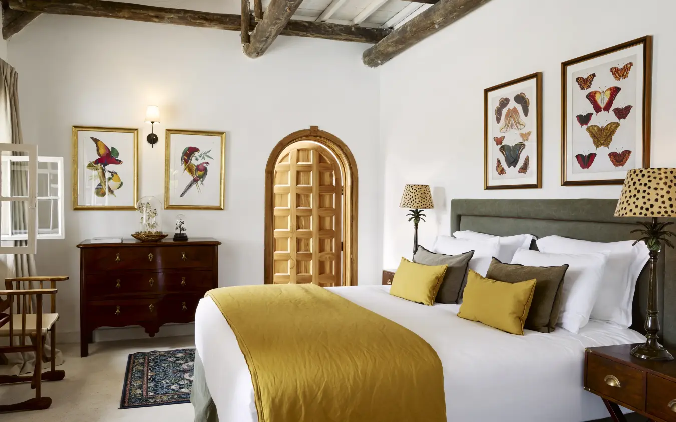 Bedroom interior with exposed beams, arched doorway and butterfly artwork, Mama Simba, Arusha, Tanzania