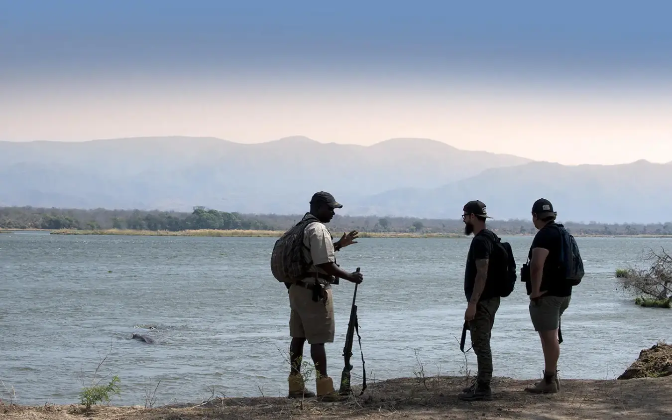 Guides discussing river expedition with mountain backdrop, Zambezi Expeditions, Mana Pools, Zimbabwe