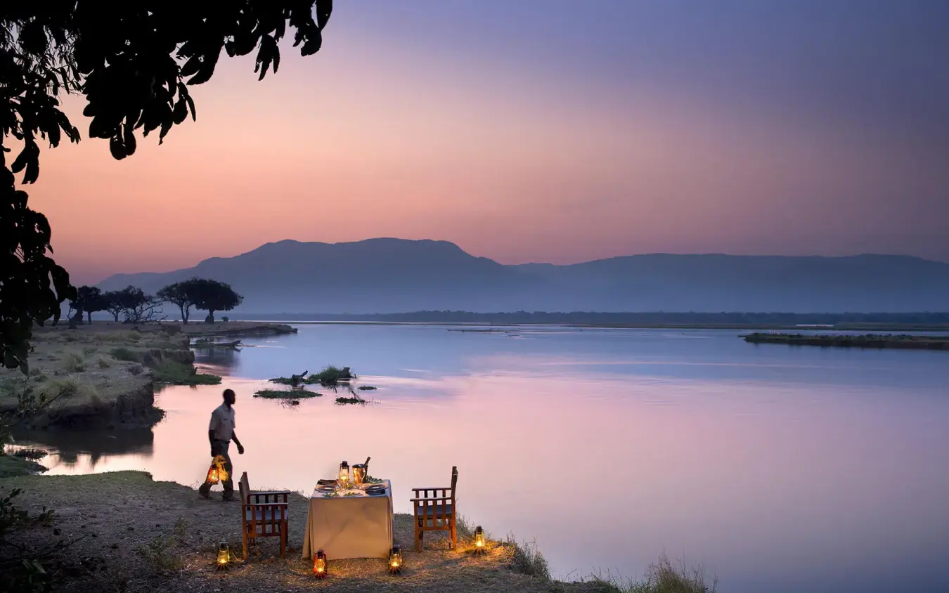 Riverside dinner setup at dusk with distant mountains, Zambezi Expeditions, Mana Pools, Zimbabwe