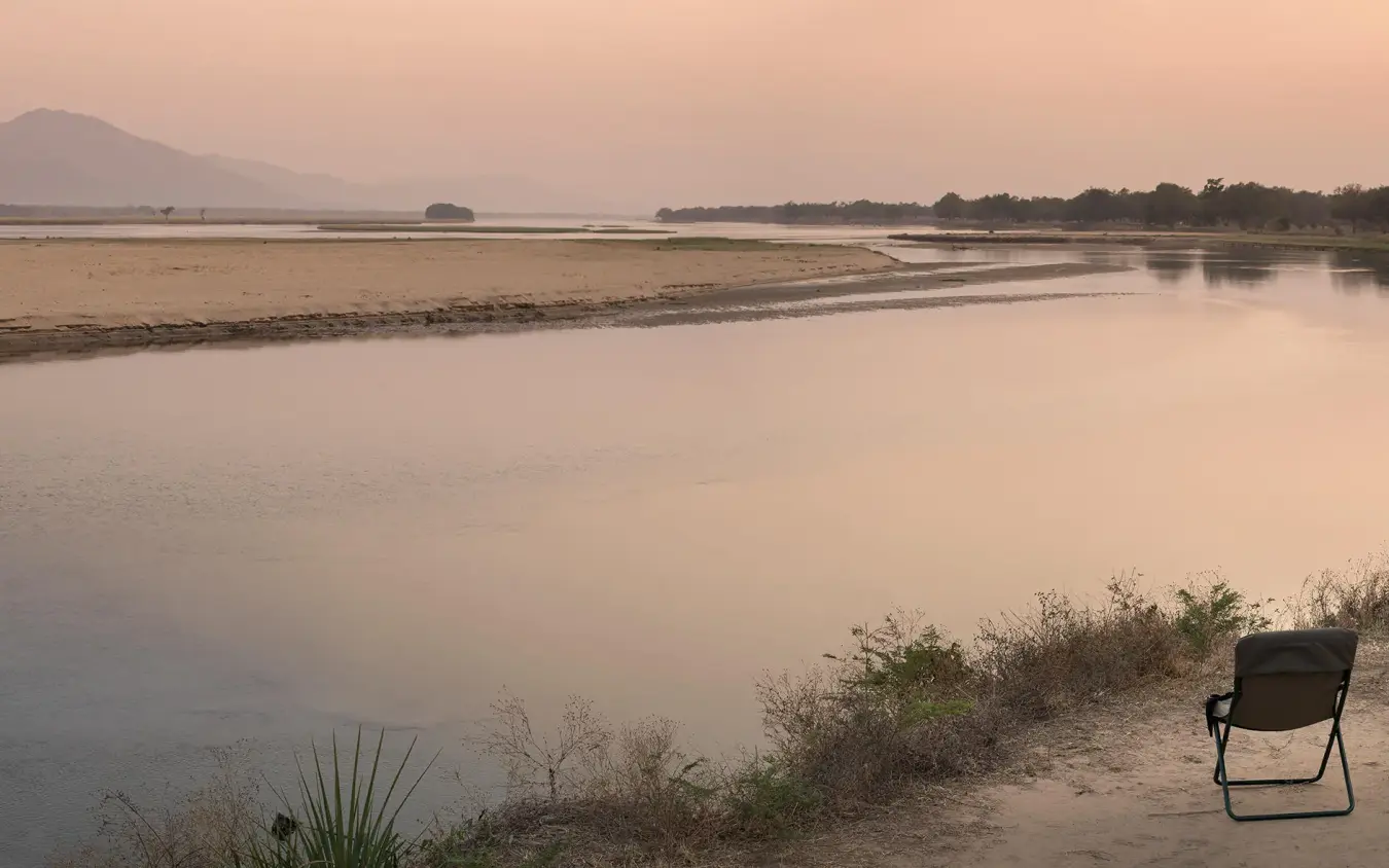 Riverside camp chairs overlooking calm water at sunset, Zambezi Expeditions, Mana Pools, Zimbabwe