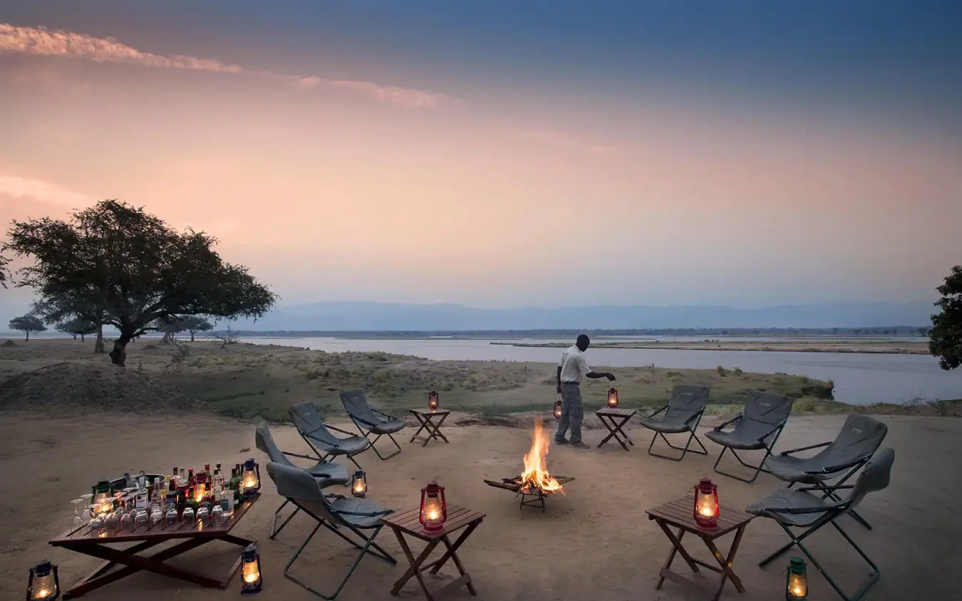 Riverside campfire setup at dusk with lanterns and chairs, Zambezi Expeditions, Mana Pools, Zimbabwe