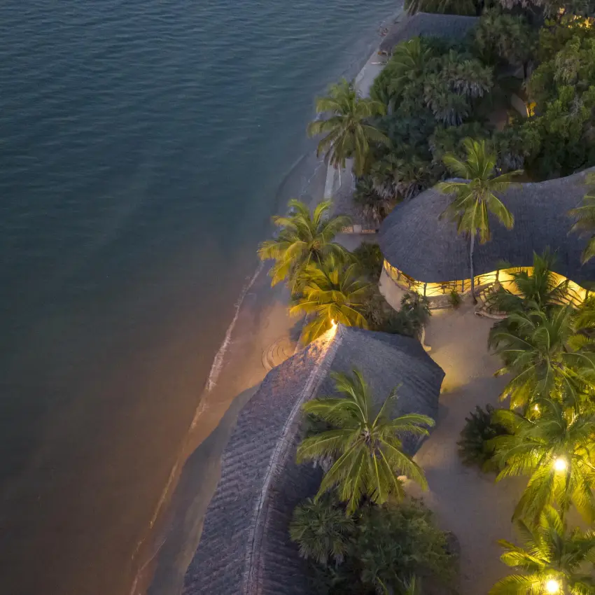 Beachfront resort with thatched bungalows at dusk, Manda Bay, Lamu Archipelago, Kenya