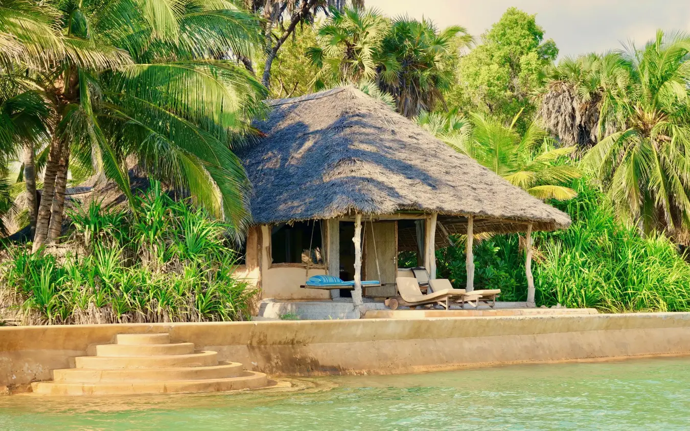 Beachfront bungalow with thatched roof overlooking turquoise water, Manda Bay, Lamu Archipelago, Kenya