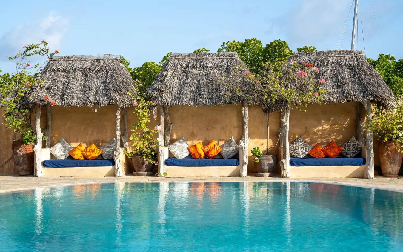 Thatched beachfront cabanas with loungers overlooking turquoise pool, Manda Bay, Lamu Archipelago, Kenya