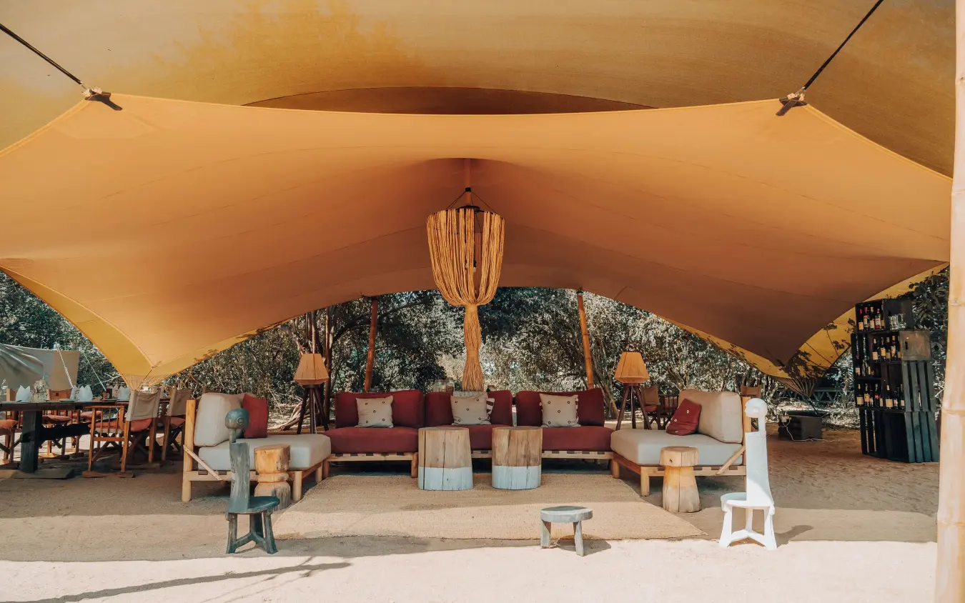 Sandy lounge area under large tan canvas tent with seating, Manyara Green Camp, Lake Manyara, Tanzania