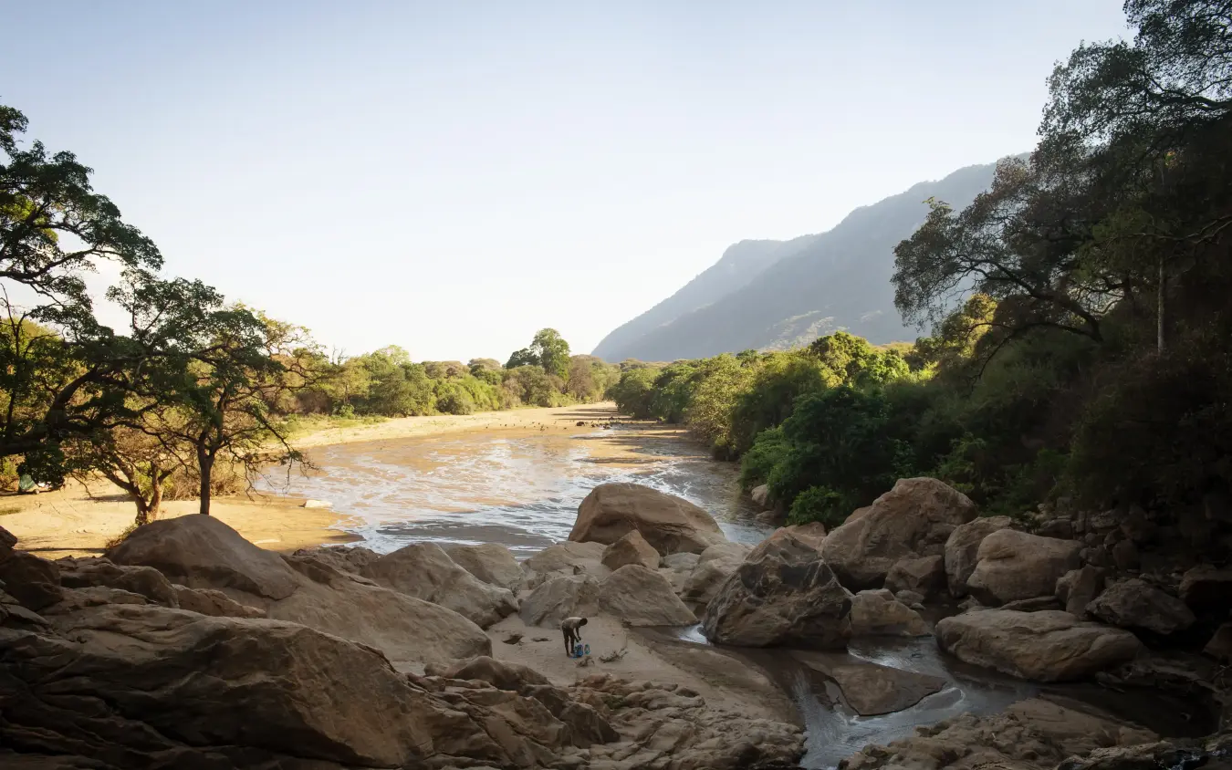 River flowing through valley with rocky foreground and mountains, Manyara Green Camp, Lake Manyara, Tanzania