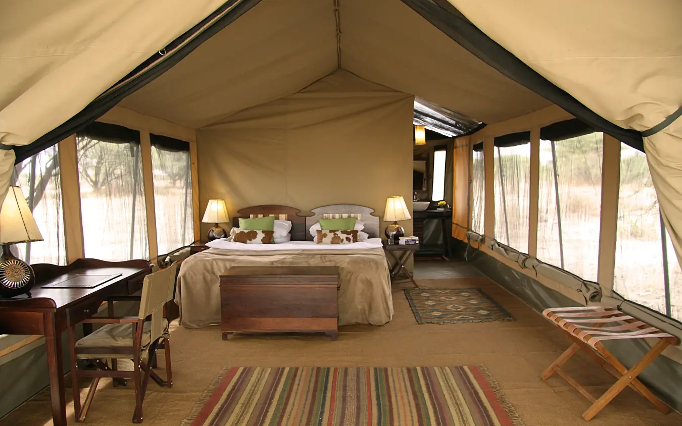 Luxury safari tent bedroom with canvas walls and large windows overlooking savanna, Manyara Ranch, Lake Manyara, Tanzania