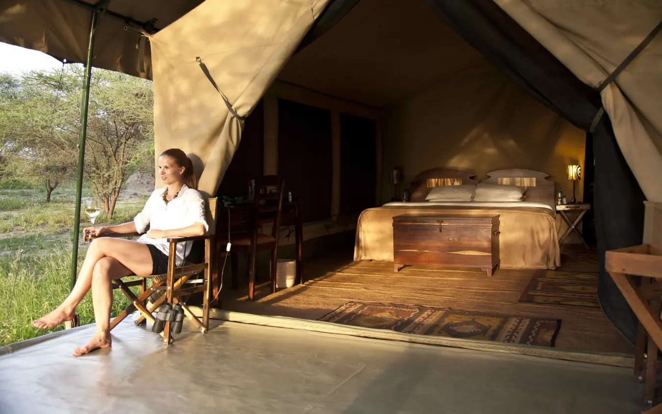 Woman relaxing on chair outside luxury canvas tent accommodation, Manyara Ranch, Lake Manyara, Tanzania
