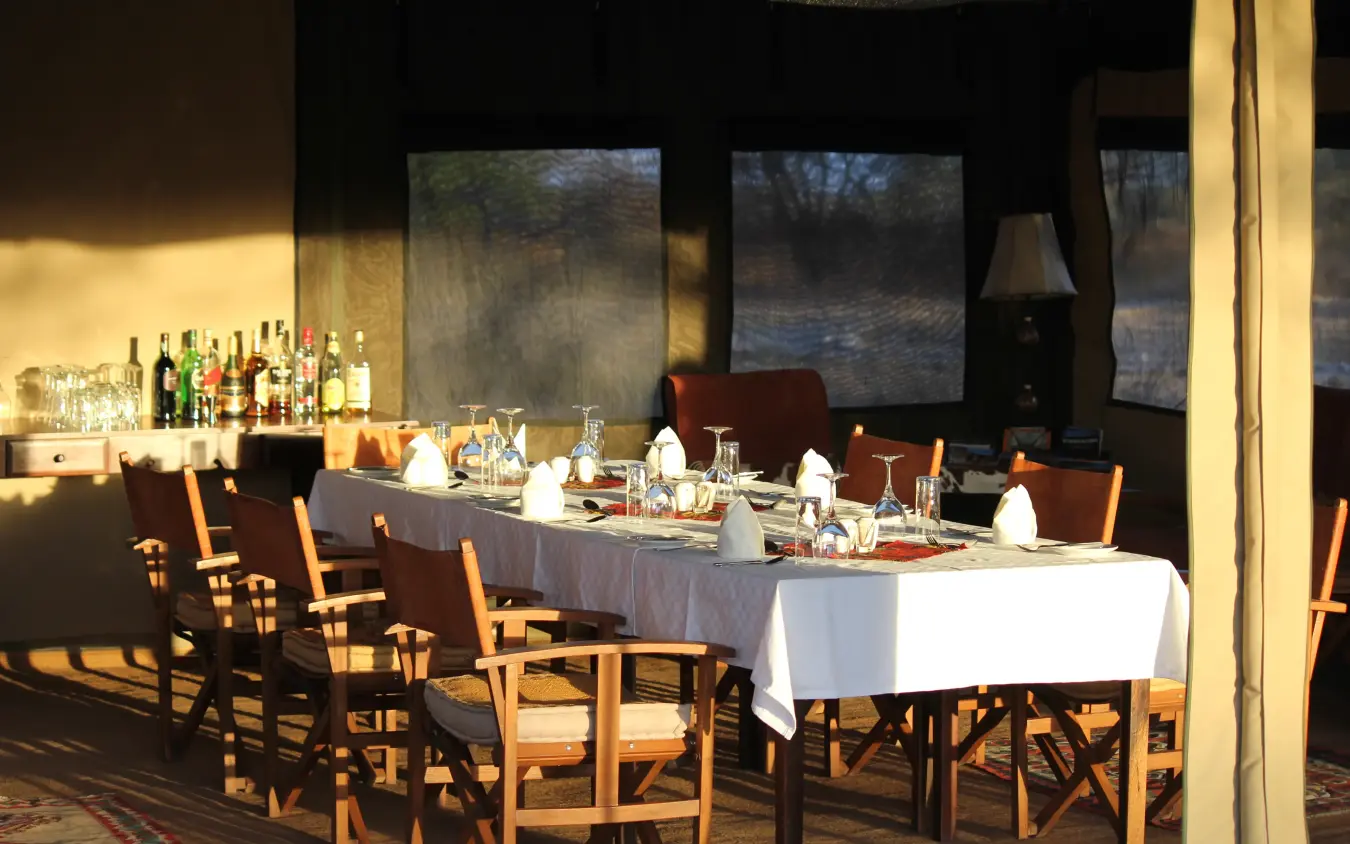 Dining room with set tables and bar overlooking river through large windows, Manyara Ranch, Lake Manyara, Tanzania