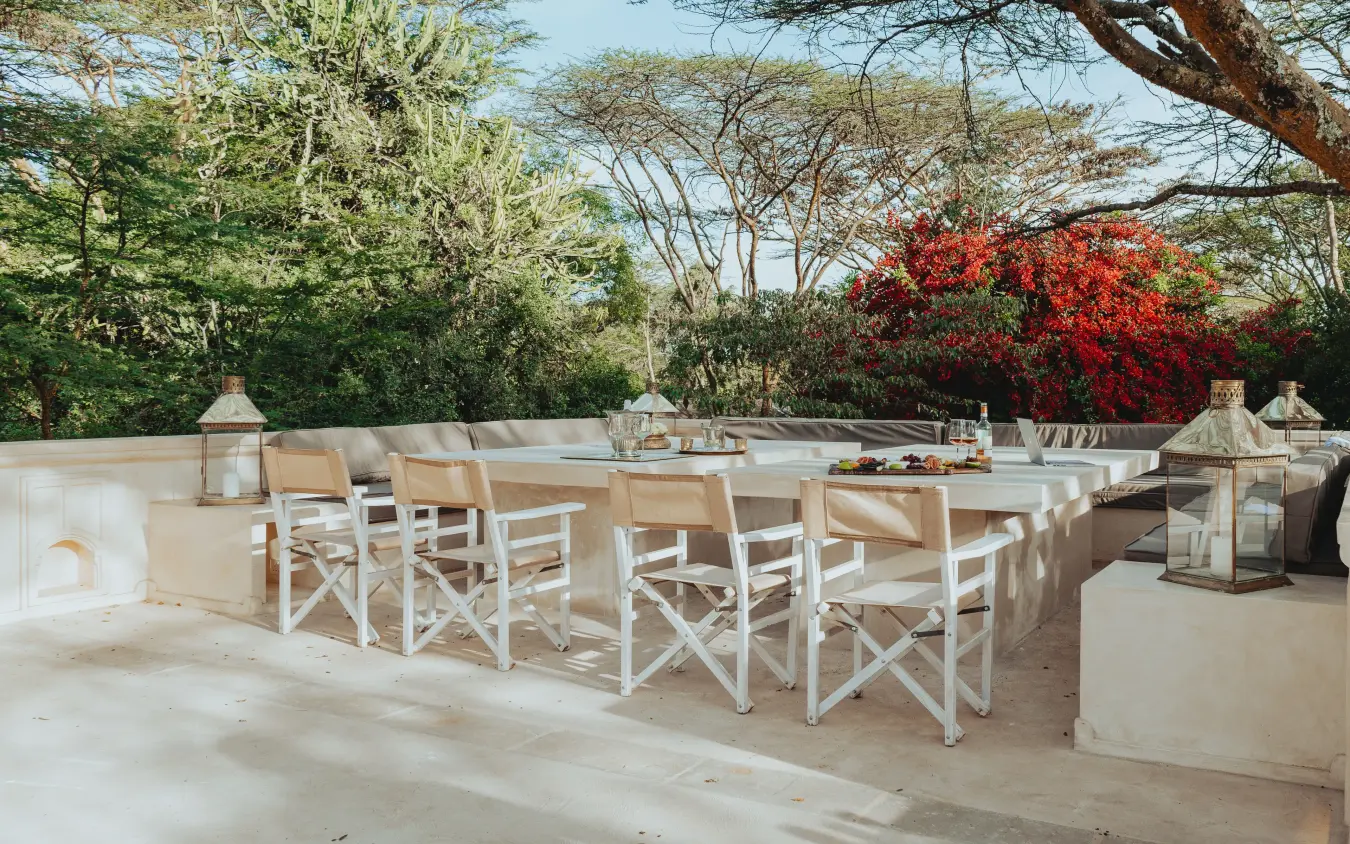 Outdoor dining terrace with white chairs and trees, Manzili House, Nairobi, Kenya