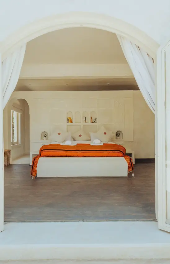 Spacious bedroom with orange bed frame and arched doorway, Manzili House, Nairobi, Kenya