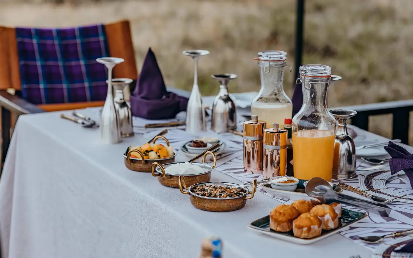 Outdoor breakfast table with pastries, juice and tableware, Mara Nyika Camp, Maasai Mara, Kenya