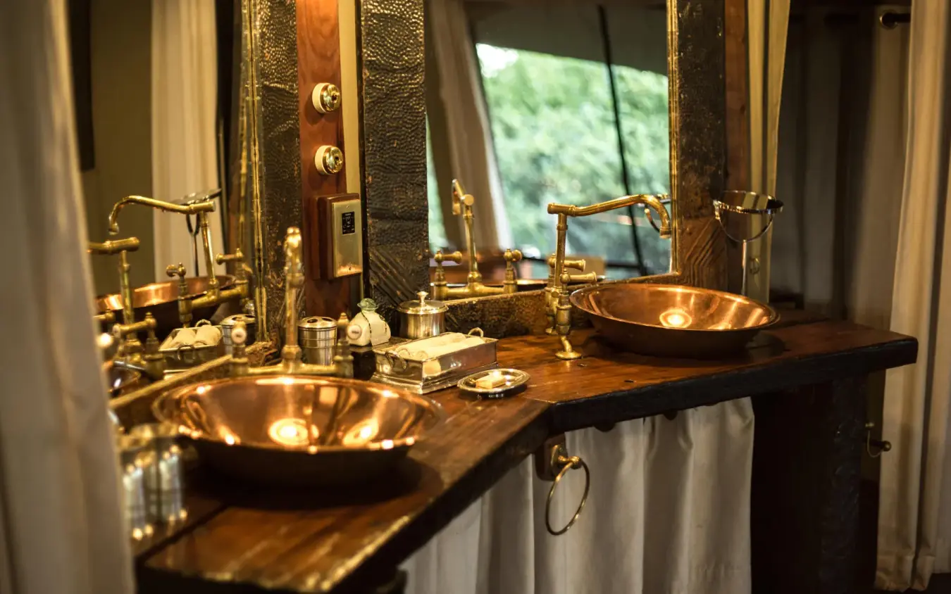 Luxury bathroom with dual copper sinks and brass fixtures, Mara Plains Camp, Maasai Mara, Kenya