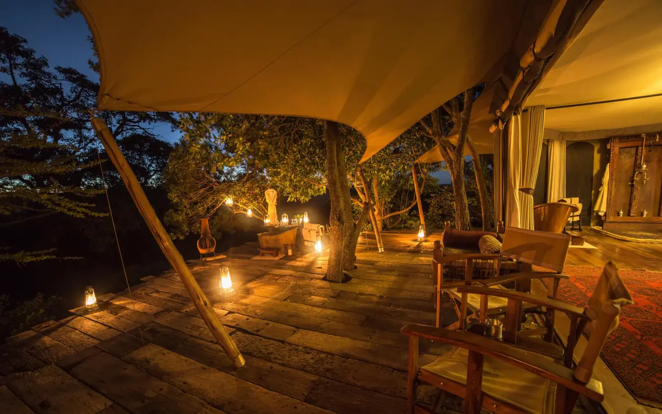 Illuminated safari lodge deck with canvas canopy at dusk, Mara Plains Camp, Maasai Mara, Kenya