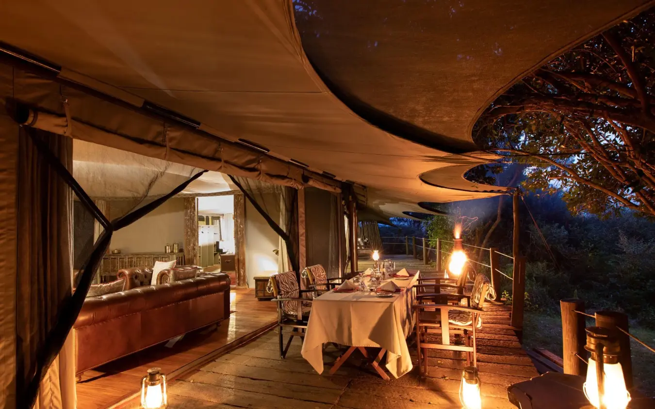 Evening dining setup on wooden deck under canvas canopy, Mara Plains Camp, Maasai Mara, Kenya