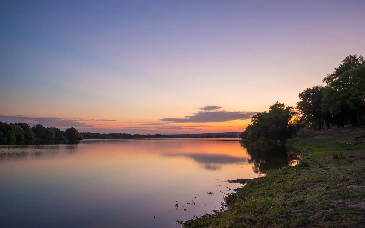 River sunset with sandy bank and treeline reflection, Matetsi River Lodge, Victoria Falls, Zimbabwe