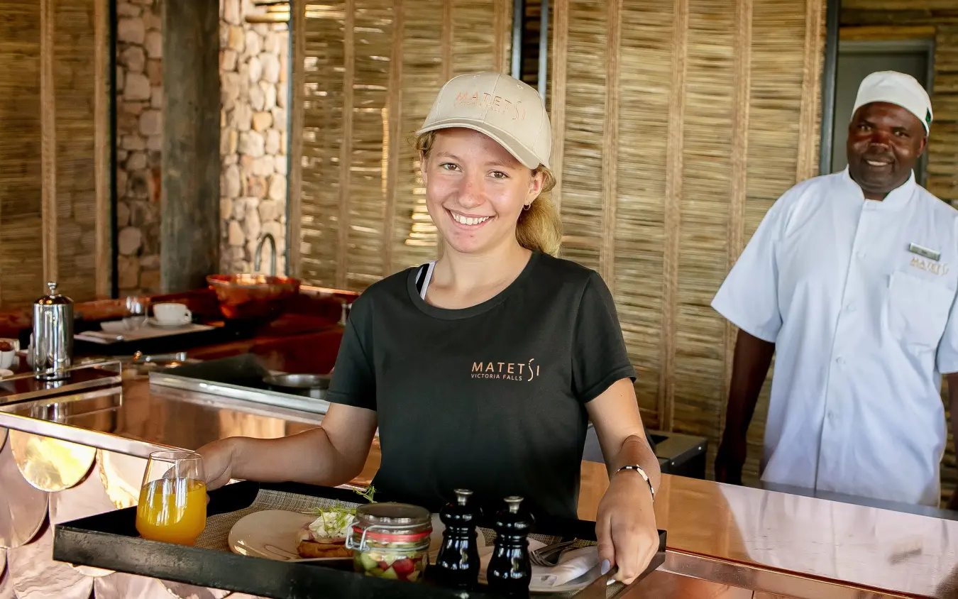 Staff member smiling at bar counter during service, Matetsi River Lodge, Victoria Falls, Zimbabwe