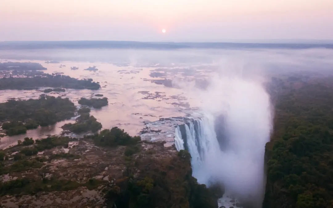 Victoria Falls at sunrise with river and forested landscape, Matetsi River Lodge, Victoria Falls, Zimbabwe