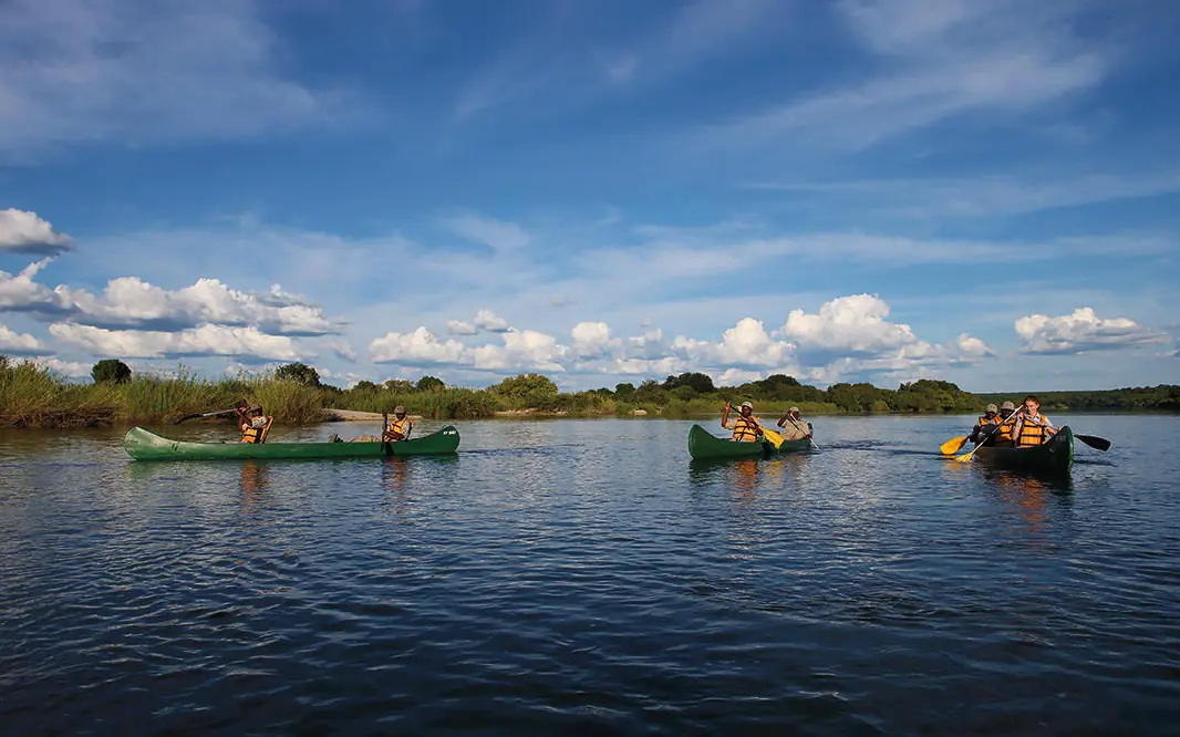 Guests in canoes paddling on wide river waterway, Matetsi River Lodge, Victoria Falls, Zimbabwe