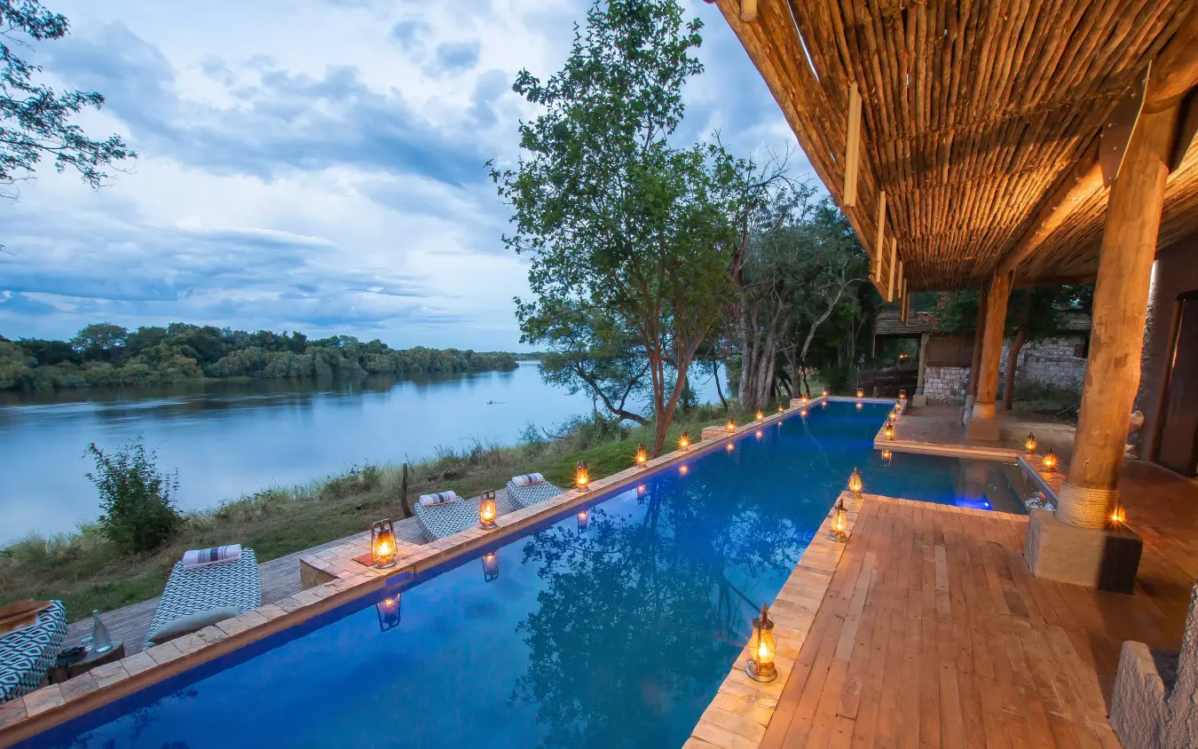 Infinity pool overlooking river at dusk with candles, Matetsi River Lodge, Victoria Falls, Zimbabwe