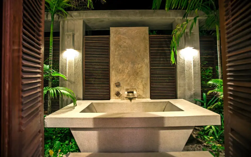 Outdoor bathroom with stone soaking tub surrounded by tropical plants and ambient lighting, Maya Kobe, Kilifi, Kenya