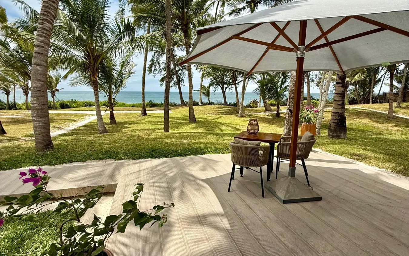 Beachfront deck with umbrella and dining setup among palm trees, Maya Kobe, Kilifi, Kenya