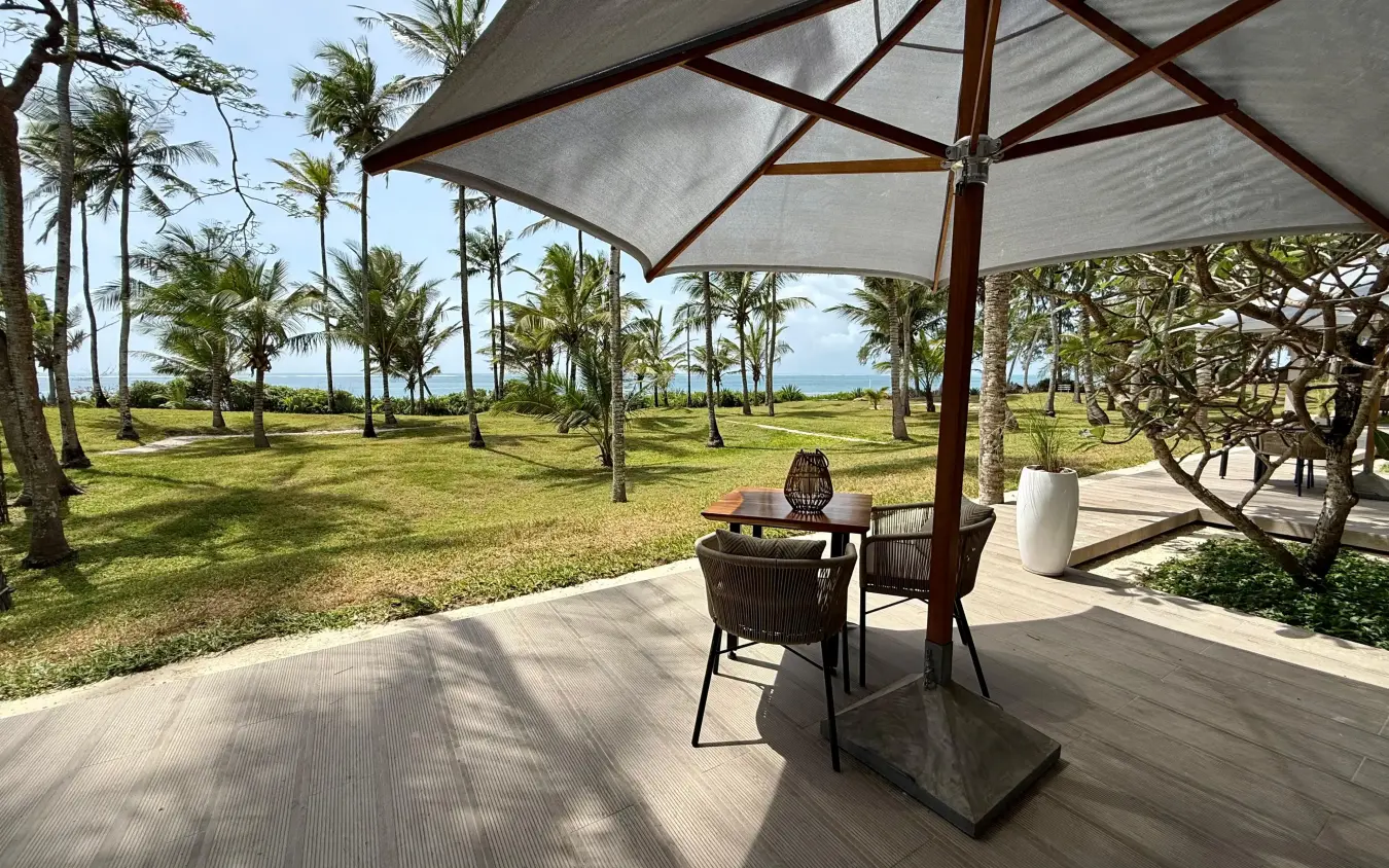 Beachfront terrace with umbrella seating overlooking palm gardens and ocean, Maya Kobe, Kilifi, Kenya