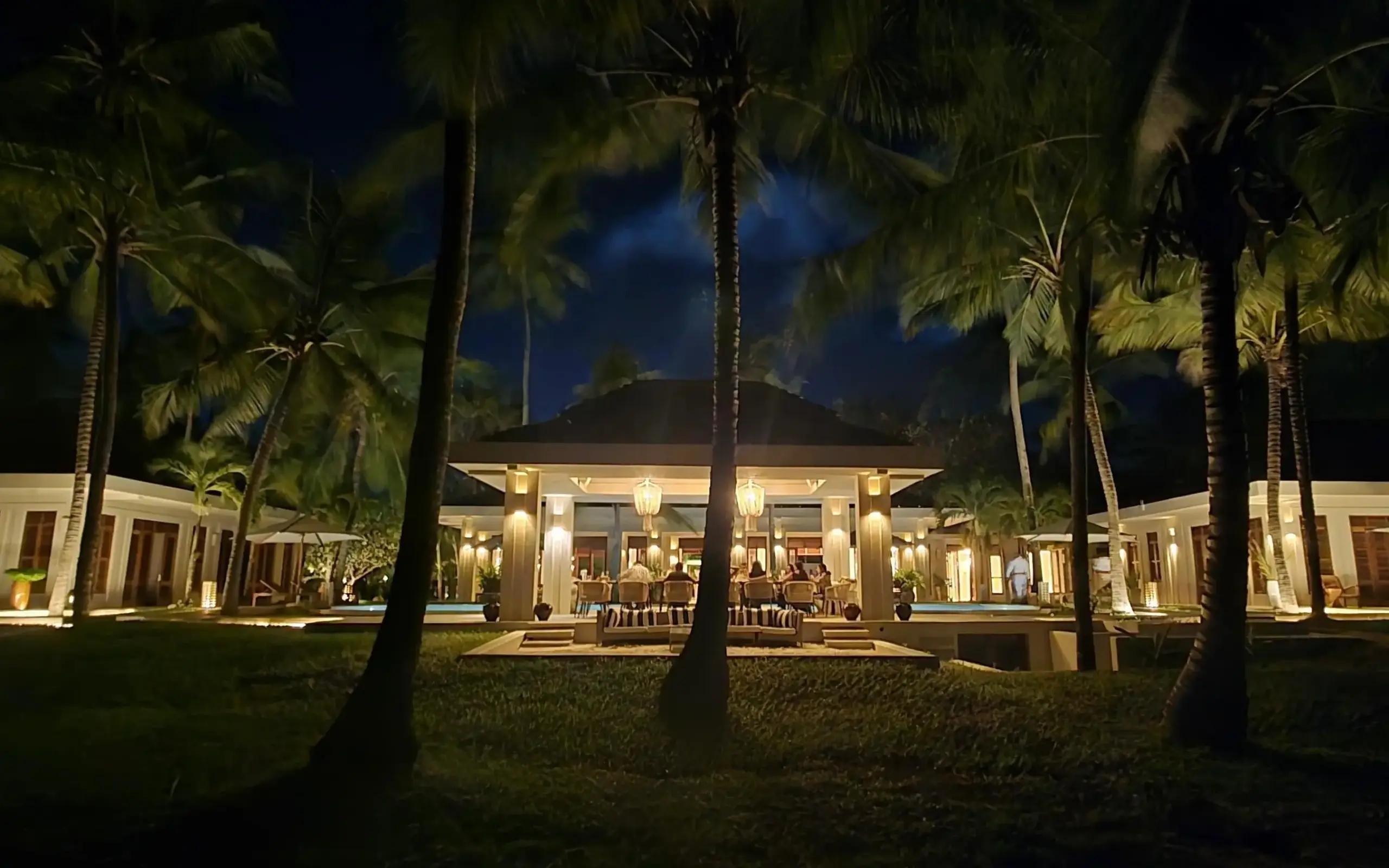 Illuminated colonial-style lodge pavilion among palm trees at night, Maya Kobe, Kilifi, Kenya