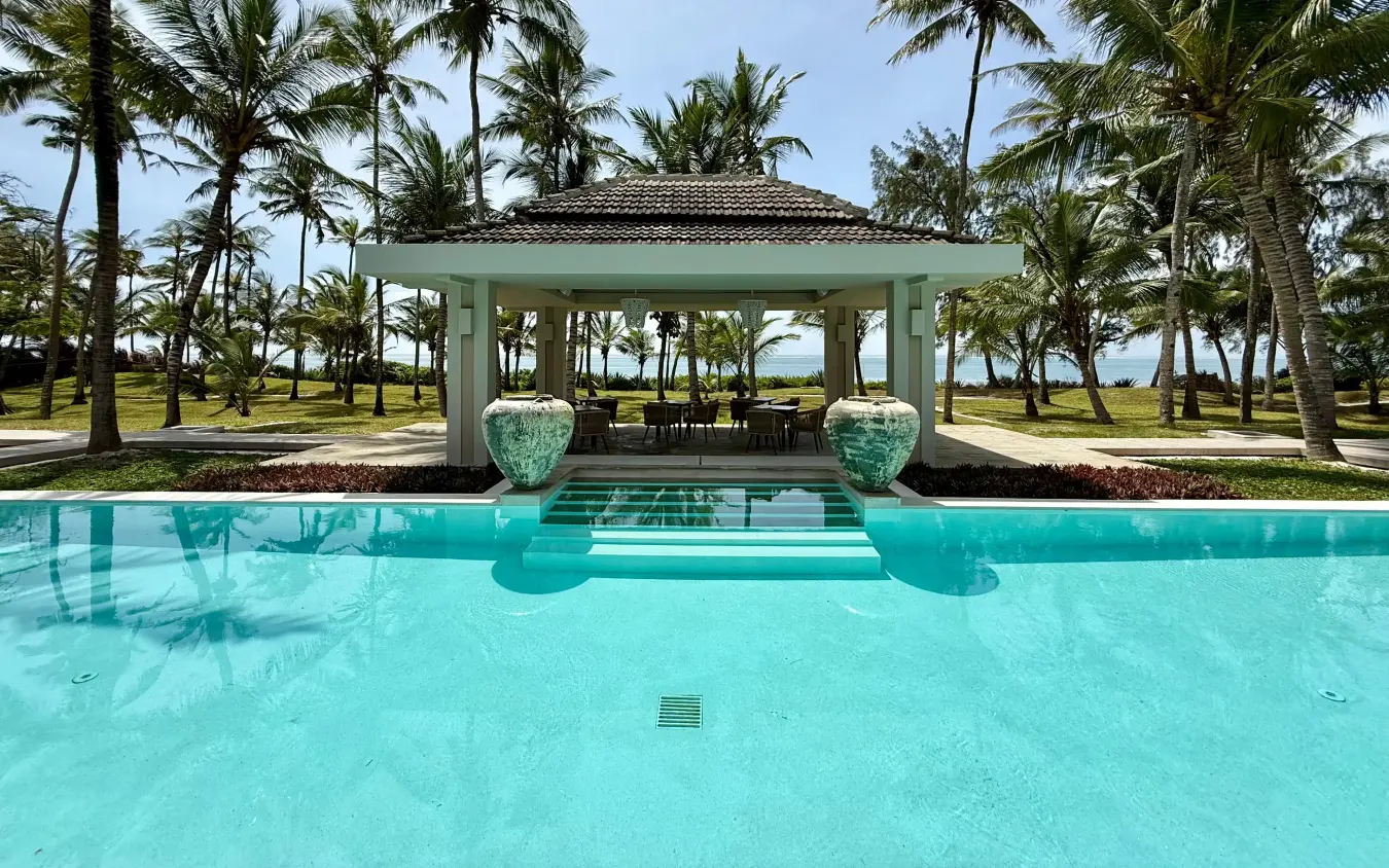 Turquoise swimming pool with tropical pavilion and palm trees overlooking water, Maya Kobe, Kilifi, Kenya