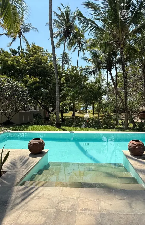 Swimming pool with tropical palms and safari lodge building nestled in trees, Maya Kobe, Kilifi, Kenya
