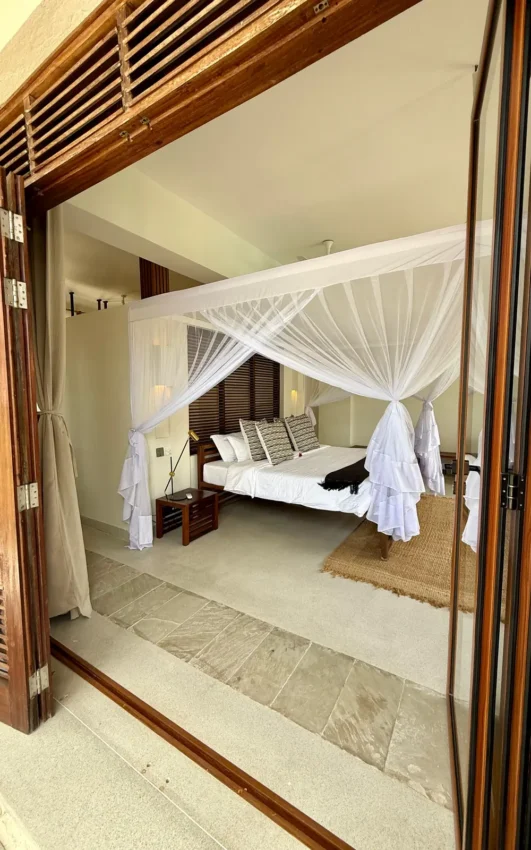 Luxury canopy bed in open-air bedroom suite with sheer white drapes, Maya Kobe, Kilifi, Kenya