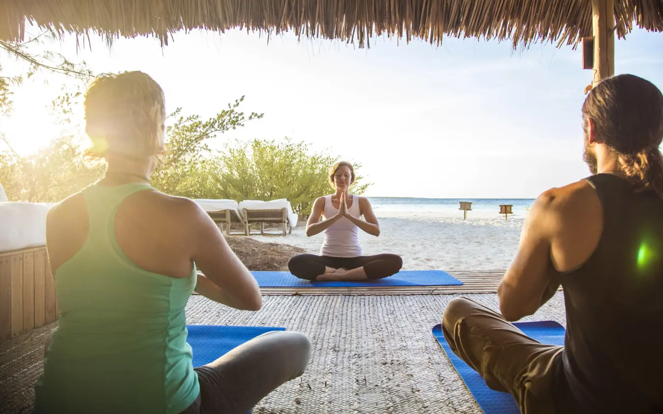 Group yoga class on beach at sunrise with ocean view, Mnemba Island, Zanzibar & Pemba, Tanzania