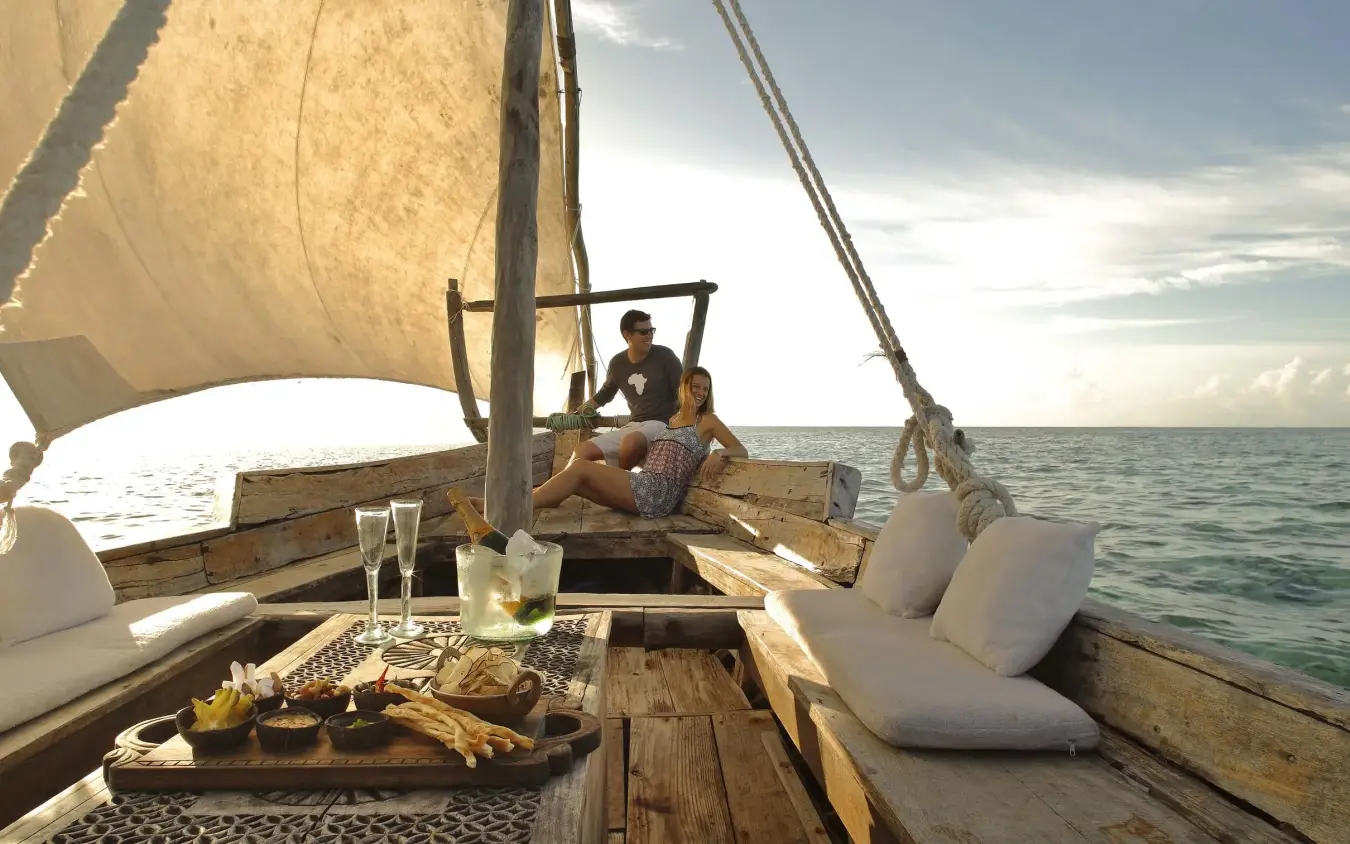 Guests sailing on traditional dhow boat at sea, Mnemba Island, Zanzibar & Pemba, Tanzania