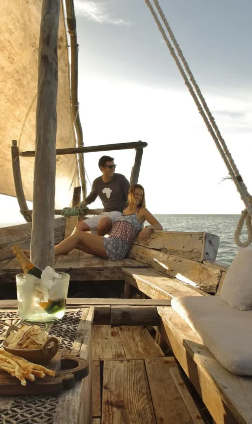 Guests sailing on traditional dhow boat at sea, Mnemba Island, Zanzibar & Pemba, Tanzania