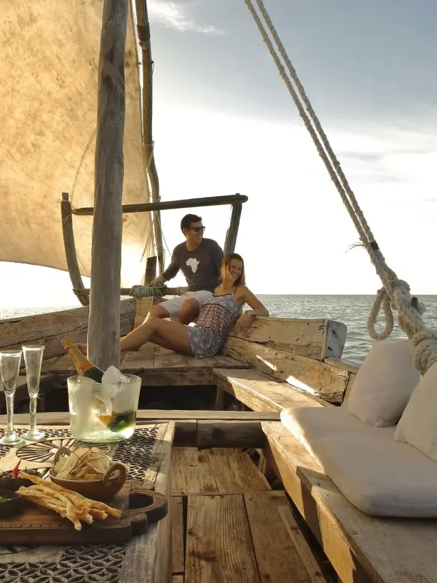 Guests sailing on traditional dhow boat at sea, Mnemba Island, Zanzibar & Pemba, Tanzania
